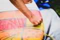 Close up view of hand waxing surf board outdoors.