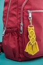 Close-up view of the handmade Macrame key chain hanging on the red backpack isolated on the tiffany blue background Royalty Free Stock Photo