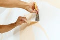 Close-up view on hands with a scraper in the process of removing wallpaper. Royalty Free Stock Photo
