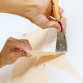 Close-up view on hands with a scraper in the process of removing wallpaper. Royalty Free Stock Photo