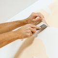 Close-up view on hands with a scraper in the process of removing wallpaper. Royalty Free Stock Photo