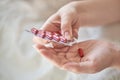 Close-up view of the hands of a sick young woman. Girl in bed holding blister and tablets or pills. Blurred background Royalty Free Stock Photo