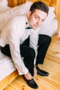 Close-up view of the handsome groom tying the wedding shoes.