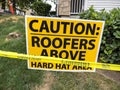 Close up view of a hard hat area sign with caution tape outside of a roof construction zone Royalty Free Stock Photo