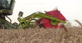 A close-up view of a harvester cutting wheat in a field. Royalty Free Stock Photo