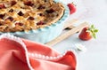 Close up view of a homemade strawberry rhubarb freshly baked pie cooling on a wooden trivet. Royalty Free Stock Photo