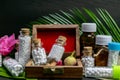 Close up view of homeopathic glass and plastic medicine bottles in wooden old box with pink flower bud, wild fruit, burlap and