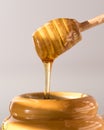 A close up view of a honey dipper dripping with honey into a honey pot. Royalty Free Stock Photo