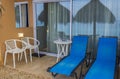 Close up view of hotel patio with sun beds and reflection in window of beach parasols with Atlantic ocean in background.