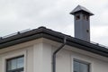 Close-up view of house with gray fold roof and plums and filing of roof overhangs with soffits and brick stone pipe covered with Royalty Free Stock Photo