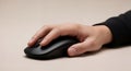 A close up view of a human hand comfortably gripping and utilizing a sleek modern black computer mouse on a Royalty Free Stock Photo