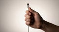 a close up view of a human hand delicately holding a silver usb cable against a neutral background Royalty Free Stock Photo