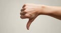 A close up view of a human hand displaying a distinct thumbs down gesture against a plain neutral light gray Royalty Free Stock Photo