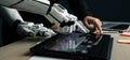 Close-Up View of a Human and a Robotic Hand Collaborating on a Digital Tablet in a Modern Workspace. Noogenesis Royalty Free Stock Photo