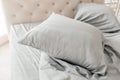 Close up view of hypoallergenic pillow in pillowcase over natural gray linen sheets in bedroom. Cotton bedding lying on