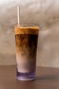 Close-up view of an iced coffee in a tall glass with cream and paper straw on a wooden table Royalty Free Stock Photo