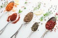 Close up view of indian spices in silver spoons near herbs on white background. Royalty Free Stock Photo