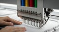 Close-Up View of an Industrial Embroidery Machine with Multicolored Thread Spools and Operator\'s Hands Royalty Free Stock Photo