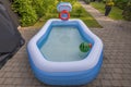 Close-up view of inflatable outdoor swimming pool filled with water in front yard.
