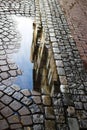 Close up view of isolated puddle after rain with reflection of house facade on cobbled street - DÃÂ¼sseldorf, Germany