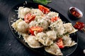 Close up view on Italian homemade ravioli stuffed with herbs, cherry tomato, parmesan, and served on plate on dark concrete backgr Royalty Free Stock Photo