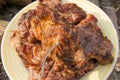Close up view of juicy pork steak on fork cooked on an open flame grill on big white plate..