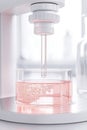 Close up view of a laboratory device dispensing liquid into a beaker filled with pink bubbly solution, representing scientific Royalty Free Stock Photo