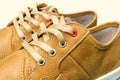 Close-up view of lacing on tan color, leather sneakers isolated on white background.