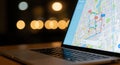 Modern laptop displaying a digital map with blurred city lights in the background Royalty Free Stock Photo