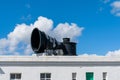 Close-up view of a large black metal foghorn on top of the roof of a lighthouse building Royalty Free Stock Photo