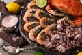 Close-up view of large dish with coked crab, baby octopuses and tiger shrimps served with lemon, lime, seashells and bowl with sea