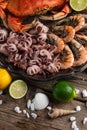 Close-up view of large dish with coked crab, baby octopuses and tiger shrimps served with lemon, lime and seashells on rustic