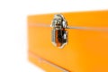 Close up view of latch on a orange metal box on white background, shallow depth of field