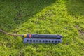 Close up view of lawn irrigation system with hose lying on green grass in garden. Royalty Free Stock Photo