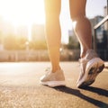 Close-up view of the legs and sneakers of a girl jogging in the city, sunny street. The concept of an active and healthy