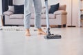 Close up view of legs and vacuum cleaner. Young woman in casual clothes is indoors in domestic room Royalty Free Stock Photo