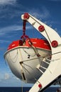 Close-up view of lifeboat on deck of a cruise ship. Orange lifeboat on mounting bracket. Royalty Free Stock Photo