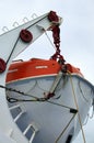 Close-up view of lifeboat on deck of a cruise ship. Orange lifeboat on mounting bracket. Royalty Free Stock Photo