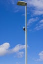 Close up view of light sensor on street lighting pole  on blue sky with rare white clouds background. Royalty Free Stock Photo