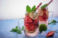 Close up view on lime and strawberry detox drink in glass mason jars on a blue background. Royalty Free Stock Photo