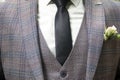 A man in a three-piece suit close-up. The close-up view of the little boutonniere on the jacket of the groom