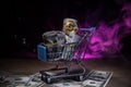 close up view of little shopping trolley full of coins on brown.Gold coins in shopping online cart isolated on brown back Royalty Free Stock Photo