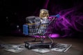 close up view of little shopping trolley full of coins isolated on brown.Gold coins in shopping online cart isolated on brown back Royalty Free Stock Photo