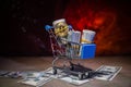 close up view of little shopping trolley full of coins on brown.Gold coins in shopping online cart isolated on brown back Royalty Free Stock Photo