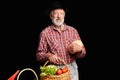 View of mature farmer picked up rich autumn harvest of vegetables