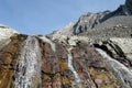 A close up view looking up at falling water from a creek rolling down the side of a steep mountain with the mountain