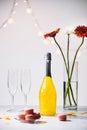 close up view of macarons, empty glasses, bottle of champagne and bouquet of gerbera flowers Royalty Free Stock Photo