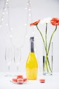 close up view of macarons, empty glasses, bottle of champagne and bouquet of gerbera flowers Royalty Free Stock Photo