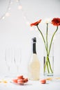 close up view of macarons, empty glasses, bottle of champagne and bouquet of gerbera flowers Royalty Free Stock Photo