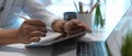 Close up view of male hand using digital tablet and holding coffee cup on worktable Royalty Free Stock Photo